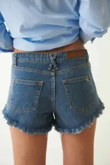 Short de denim azul con lavado medio y detalles de desgaste, tiro alto y ruedo deshilachado.