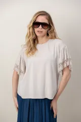 Remera de algodón color blanco, con cuello redondo y mangas cortas holgadas que presentan detalles de encaje broderie.