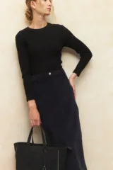 Maxifalda de pana de tiro alto, con cierre frontal, botón metálico, cuatro bolsillos y abertura trasera.