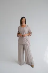 Blusa de diseño holgado en color beige, compuesta por una capa superior de tela semitransparente y una capa inferior con detalle de lentejuelas. Presenta mangas cortas con bordes decorados con lentejuelas y cuello redondo.