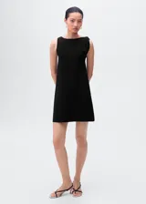 Vestido corto negro de corte recto y diseño minimalista, con cuello barco y tirantes asimétricos.
