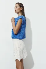 Chaleco azul de punto calado con cuello redondo, sin mangas, cierre frontal con botones y dos bolsillos de parche en la parte delantera.