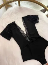 Body entallado de lycra color negro, con escote pronunciado decorado con encaje y microtul. Presenta mangas cortas de encaje y un collarín regulable desmontable integrado al diseño.