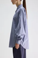 Camisa de silueta oversize de algodón color celeste, con cuello clásico, cierre frontal con botones, hombros caídos, bolsillo aplicado en el pecho y puños abotonados.