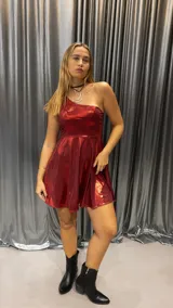 Vestido corto de un solo hombro, confeccionado en tela metalizada color bordó con acabado brillante y falda acampanada.