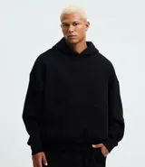 Buzo de algodón negro con capucha y bolsillo canguro delantero. Presenta un corte recto y holgado (boxy fit) con puños y bajo terminados en elástico.