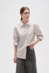 Camisa de lyocell con estampado de rayas verticales en tonos beige y blanco, corte holgado, cuello clásico y puños anchos en color blanco sólido.