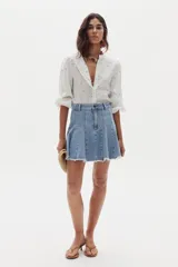 Minifalda blanca de denim con diseño evasé, godets que aportan movimiento y ruedo desflecado.