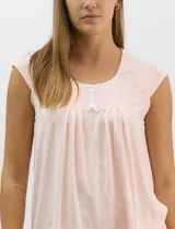 Pijama compuesto por remera sin mangas con escote redondo, botones frontales y detalle de puntilla, acompañado de un pantalón capri con cintura elástica. Presenta un estampado floral en tonos rosados sobre base gris.