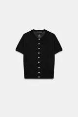 Chaqueta de punto pointelle negra, de manga corta y cuello redondo, con diseño de estrellas y cierre frontal con botones.