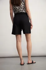 Short negro de tiro alto con lazo de tela para ajustar en la cintura y bolsillos laterales. El largo es por encima de la rodilla.