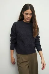 Sweater de punto con textura en relieve, cuello redondo y mangas largas con puños ajustados.