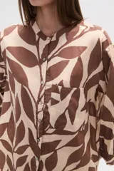Camisa de corte holgado con estampado animal print tipo cebra en tonos negro y beige. Presenta cuello mao, cierre frontal con botones y un bolsillo aplicado en el pecho.