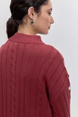 Sweater de tejido de punto color bordó, con cuello alto, mangas largas con puños ajustados y diseño de trenzas verticales.