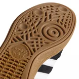 Championes Adidas Busenitz Pro, modelo de skate en color negro con las icónicas tres tiras blancas laterales y suela de goma color caramelo. Presenta una lengüeta larga característica y detalles en dorado.