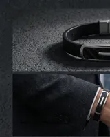 Pulsera masculina con banda de goma negra con textura de fibra de carbono y placa central de acero inoxidable.