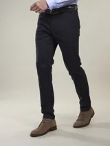 Pantalón de vestir azul marino, de corte recto, con bolsillos laterales y traseros. Se ajusta a la cintura con cinturón de cuero marrón.