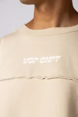 Buzo oversize de corte boxy, confeccionado en algodón rústico de alto gramaje en color beige. Presenta cuello redondo con borde crudo, mangas largas y una estampa frontal con el texto VCP delimitado por líneas horizontales blancas.