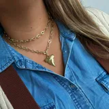 Collar dorado de doble cadena con dije de diente de tiburón.