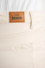 Pantalón de jean color crudo, de corte recto, tiro medio y ruedo ancho con detalle de línea roja.