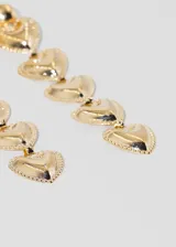 Par de caravanas largas doradas con forma de corazones colgantes.