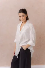 Camisa lila oversize de algodón con bordado floral calado tipo broderie, cuello camisero, manga larga y abotonadura frontal.