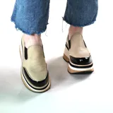 Zapatos tipo mocasín de cuero color beige texturado, con plataforma alta a rayas en tonos marrón, negro y blanco, y puntera de charol negro.