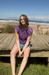 Musculosa tejida en punto calado, color violeta, con diseño sin mangas y detalle de flecos en los hombros.