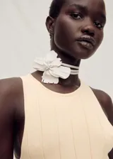 Vestido midi de punto fino con diseño plisado en la parte inferior y corte evasé. Presenta cuello halter, diseño sin mangas y una textura acanalada en el cuerpo.