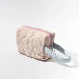 Neceser acolchado color rosa con diseño de flores, cierre superior con cremallera rosa y tirador celeste, y asa lateral celeste.