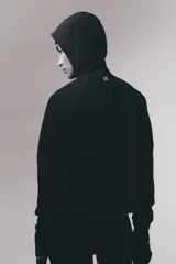 Campera deportiva de running color negro, confeccionada en tejido funcional DryMove. Presenta un diseño de corte holgado con medio cierre frontal, capucha de doble capa, mangas raglán con abertura para el pulgar y bolsillos laterales con cierre. Incluye cordón elástico ajustable en el bajo y detalles reflectantes.