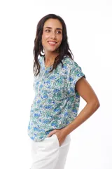 Blusa estampada con flores azules y verdes, de manga corta con cierre metálico en el frente.