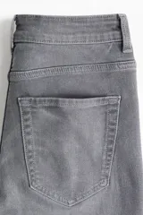 Jeans de tiro alto, color gris oscuro lavado, con corte ajustado en la parte superior y pierna acampanada (flare) desde la rodilla hasta el bajo. Presenta cinco bolsillos y cierre frontal con botón.