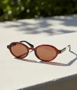 Lentes de sol con montura ovalada de acetato color marrón oscuro (maroon) y lentes polarizadas color marrón.
