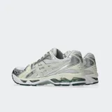 Championes Asics Gel Kayano 14 de estilo retro, color plateado y gris con detalles en dorado, confeccionados con malla y revestimientos sintéticos metalizados, equipados con tecnología GEL en la suela para mayor amortiguación.