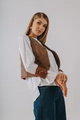 Chaleco de cuero sintético metalizado en color dorado, con escote en V, cierre frontal de botones y detalles de tachas metálicas en los bordes.