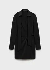 Vestido corto de color negro con escote cruzado en V y cuello con solapa. Presenta mangas largas con puños abotonados, pliegues decorativos en la cintura y un lazo desmontable en el cuello.