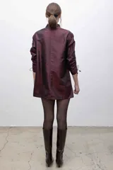 Vestido corto color borgoña, con capucha, cierre frontal y mangas largas fruncidas.