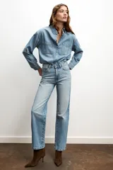 Jeans celeste de tiro alto, corte recto y largo, con cinco bolsillos y cierre frontal con cremallera y botón.