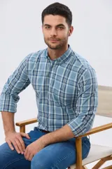 Camisa de manga larga de calce slim, con diseño a cuadros en tonos azul oscuro, verde y blanco. Presenta cuello camisero con botones y bolsillo ojal en el pecho con detalle bordado.