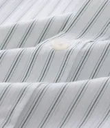 Camisa de manga larga con diseño de rayas verticales, cuello clásico y cierre frontal con botones. Confeccionada en una mezcla de algodón, poliamida y elastano, presenta una estampa gráfica en la espalda con la frase Echoes of a Restless Beat.