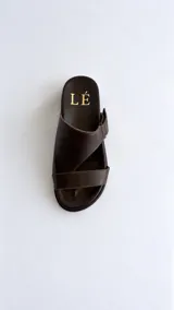 Sandalias de cuero color marrón con diseño asimétrico de tiras y plantilla anatómica. Tienen ajuste lateral con velcro y suela plana.