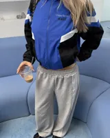 Campera deportiva de diseño colorblock en tonos azul, negro y blanco, con cierre frontal y cuello alto. Presenta detalles de franjas y un pequeño estampado en el pecho con la inscripción "Uruguay Run Club".