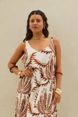 Vestido largo color crudo con estampado botánico en tonos marrones, de tirantes anchos, escote redondo y falda con vuelo escalonado.