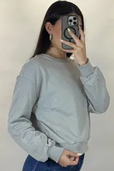 Buzo de cuello redondo y manga larga, color negro, con diseño de pequeños puntos brillantes distribuidos por toda la prenda. Presenta puños y ruedo acanalados.
