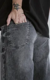 Pantalón de denim 100% algodón, color negro con lavado ácido/desgastado. Diseño de cinco bolsillos y calce wide leg.