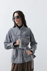 Sobrecamisa de jean color negro con silueta relajada, cuello camisero, cierre frontal con botones metálicos, bolsillos frontales y cinturón ajustable en la cintura.