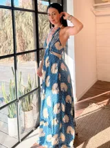 Vestido largo con estampado de hojas en tonos verde y blanco, con escote halter y espalda descubierta.