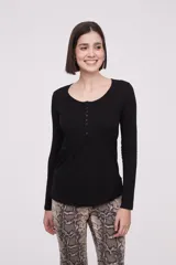 Remera blanca de manga larga, entallada, con cuello redondo y una hilera de botones en el frente. Incluye un pequeño bolsillo decorativo en el pecho.