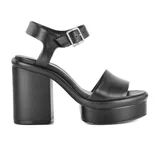 Sandalias negras de cuero sintético con plataforma y tacón bloque altos. Tira ancha sobre los dedos y pulsera al tobillo con hebilla metálica.